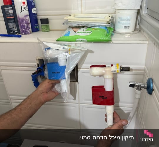 אדם מחזיק חלקי צנרת וכלי עבודה בחדר אמבטיה